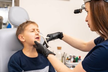 Burun muayenesi, küçük çocuk, sarışın genç endişeli, otoların ofisinde oturuyor, doktordaki burun deliklerini inceliyor, duygusal. Tedavi ilaçları