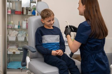 Bir klinikte otoskoplu bir doktor tarafından muayene edilen sarışın bir çocuğun portresi, duygusal bir şekilde sandalyede oturuyor. Yakın çekim, tıbbi muayene.