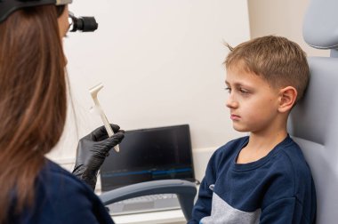 Burun muayenesi ve muayenesi, küçük çocuk, gülümseyen sarışın genç, otolaringolojistin ofisinde oturuyor, doktordaki burun deliklerini inceliyor, güvenen, duygusal, gülümseyen. Fiziksel muayene.