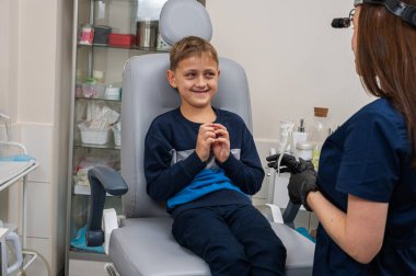 Boyun muayenesi, üst çene sinüsleri, yüze masaj, küçük bir çocuk, sarışın bir genç endişeli, otoların muayenehanesinde oturuyor, doktor burun kemiğini muayene ediyor.