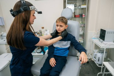 Boyun muayenesi, üst çene sinüsleri, yüze masaj, küçük bir çocuk, sarışın bir genç endişeli, otoların muayenehanesinde oturuyor, doktor burun kemiğini muayene ediyor.