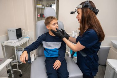 Boyun muayenesi, üst çene sinüsleri, yüze masaj, küçük bir çocuk, sarışın bir genç endişeli, otoların muayenehanesinde oturuyor, doktor burun kemiğini muayene ediyor.