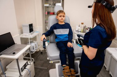 Boyun muayenesi, üst çene sinüsleri, yüze masaj, küçük bir çocuk, sarışın bir genç endişeli, otoların muayenehanesinde oturuyor, doktor burun kemiğini muayene ediyor.