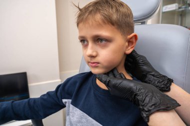 Boynun incelenmesi, üst çene sinüsleri, yüze masaj yapılması, küçük bir çocuk, sarışın bir genç, otolarngolojistin ofisinde otururken, doktor burun deliklerini ve boynu duygusal olarak inceler. Tedavi ilaçları