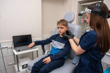 Boynun incelenmesi, üst çene sinüsleri, yüze masaj yapılması, küçük bir çocuk, sarışın bir genç, otolarngolojistin ofisinde otururken, doktor burun deliklerini ve boynu duygusal olarak inceler. Tedavi ilaçları