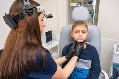 Boyun muayenesi, üst çene sinüsleri, yüze masaj, küçük bir çocuk, sarışın bir genç endişeli, otoların muayenehanesinde oturuyor, doktor burun kemiğini muayene ediyor.