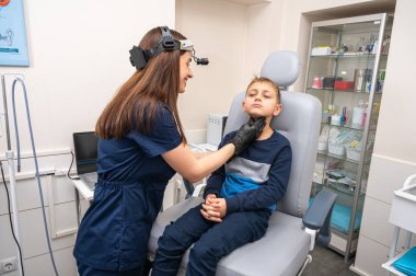 Boyun muayenesi, üst çene sinüsleri, yüze masaj, küçük bir çocuk, sarışın bir genç endişeli, otoların muayenehanesinde oturuyor, doktor burun kemiğini muayene ediyor.