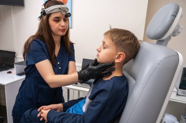 Boyun muayenesi, üst çene sinüsleri, yüze masaj, küçük bir çocuk, sarışın bir genç endişeli, otoların muayenehanesinde oturuyor, doktor burun kemiğini muayene ediyor.