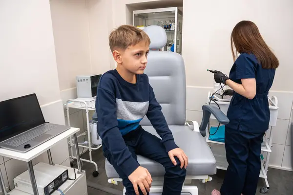 Küçük bir çocuk, sarışın bir genç, otolaringolojistin ofisinde oturuyor, doktorda kulak muayenesi yaptırıyor, endişeli, duygusal, ama gülümsüyor. Fiziksel muayene.