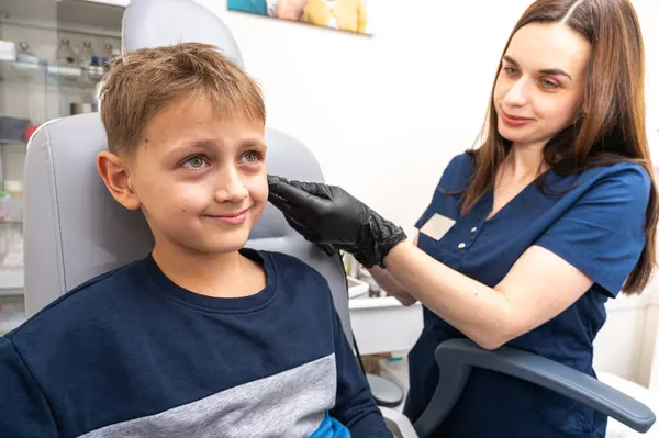 Küçük bir çocuk, sarışın bir genç, otolaringolojistin ofisinde oturuyor, doktorda kulak muayenesi yaptırıyor, endişeli, duygusal, ama gülümsüyor. Fiziksel muayene.