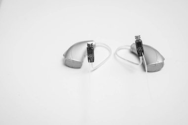 Siyah beyaz fotoğraf, işitme cihazı beyaz arka planda izole edilmiş. Kapalı görüşler, işitme cihazları