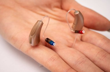 Palmiye içinde işitme cihazı beyaz arka planda izole. Yakın çekim görüntüler, üst görünüm, işitme aygıtları