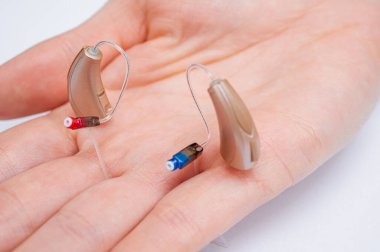 Palmiye içinde işitme cihazı beyaz arka planda izole. Yakın çekim görüntüler, üst görünüm, işitme aygıtları