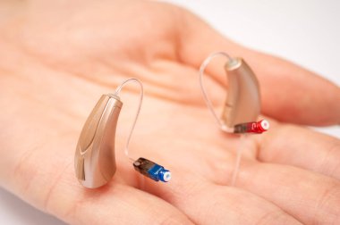 Palmiye içinde işitme cihazı beyaz arka planda izole. Yakın çekim görüntüler, üst görünüm, işitme aygıtları