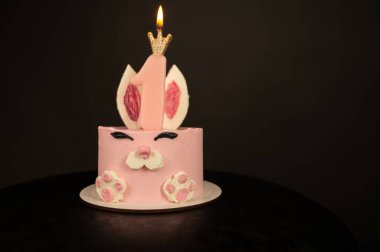 Koyu arkaplanda küçük bir kız için pembe renkli pasta.