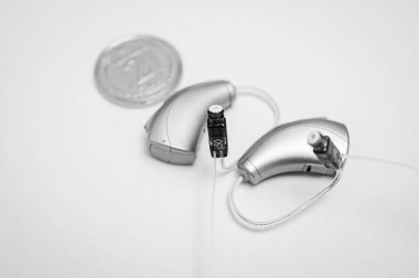 Siyah beyaz fotoğraf, işitme cihazı beyaz arka planda izole edilmiş. Yakın çekim, sağırlar için işitme cihazı