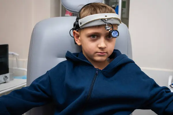 little emotional boy, fair-haired teenager, sitting in the otolaryngologist\'s office, waiting for the doctor for an examination, but smiling. Physical examination