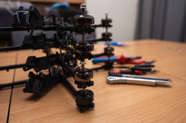 İHA çerçeve montajı, bükme, lehimleme, monte etme, insansız hava aracı parçalarının birleştirilmesi. Yakın plan, yüksek teknoloji, ahşap masadaki dronlar. Yeni teknolojiler