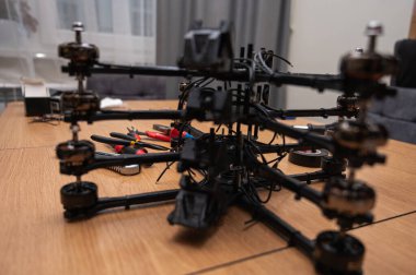 İHA çerçeve montajı, bükme, lehimleme, monte etme, insansız hava aracı parçalarının birleştirilmesi. Yakın plan, yüksek teknoloji, ahşap masadaki dronlar. Yeni teknolojiler