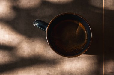 Tahta sehpada bir fincan kahve, arka plan, sabah ışığı ışınları, üst manzara, yazmak için yer