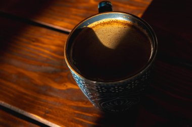 bir fincanda köpüklü kahve, ahşap bir masa, arka plan, sabah ışığı ışınları, kontrast, üst görüş, yazma yeri, seçici odak, sabah kahvesi