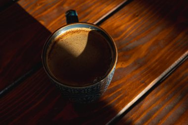 bir fincanda köpüklü kahve, ahşap bir masa, arka plan, sabah ışığı ışınları, kontrast, üst görüş, yazma yeri, seçici odak, sabah kahvesi