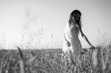 Siyah beyaz fotoğraf, seçici odak, geniş bir alanda genç bir kız, gülümsüyor, bir elbise içinde, Ukrayna 'nın yazıtları, tarlası ve doğası için bir yer.