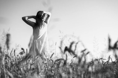 Siyah beyaz fotoğraf, seçici odak, geniş bir alanda genç bir kız, gülümsüyor, bir elbise içinde, Ukrayna 'nın yazıtları, tarlası ve doğası için bir yer.