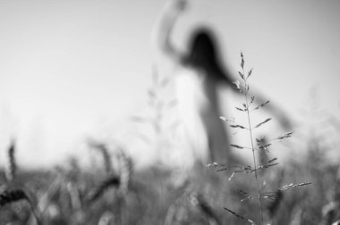 Siyah beyaz fotoğraf, seçici odak, geniş bir alanda genç bir kız, gülümsüyor, bir elbise içinde, Ukrayna 'nın yazıtları, tarlası ve doğası için bir yer.