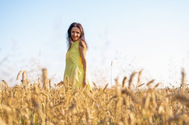 Buğday tarlasında güzel bir genç kızın portresi, gülümsüyor, sarı bir elbise içinde, yazacak yer, tarlalar ve Ukrayna doğası.