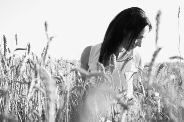 Doğadaki buğday tarlasında, batan güneşin ışınlarında, sarı bir elbise, arka plan ışığı, gün batımı, gülümseme, tarlalar ve Ukrayna 'nın doğasıyla güzel, genç ve duygusal bir kızın klasik fotoğrafı.