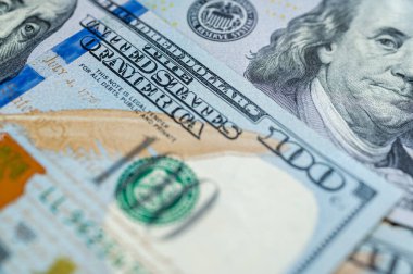 100 dolarlık banknotun yakın plan görüntüsü. Karmaşık detayları, güvenlik özelliklerini ve canlı renkleri vurguluyor. Finans, bankacılık ve zenginlik temaları için mükemmel