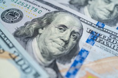 100 dolarlık banknotun yakın plan görüntüsü. Karmaşık detayları, güvenlik özelliklerini ve canlı renkleri vurguluyor. Finans, bankacılık ve zenginlik temaları için mükemmel