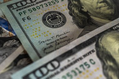 100 dolarlık banknotun yakın plan görüntüsü. Karmaşık detayları, güvenlik özelliklerini ve canlı renkleri vurguluyor. Finans, bankacılık ve zenginlik temaları için mükemmel