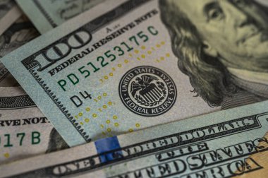 100 dolarlık banknotun yakın plan görüntüsü. Karmaşık detayları, güvenlik özelliklerini ve canlı renkleri vurguluyor. Finans, bankacılık ve zenginlik temaları için mükemmel