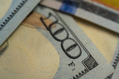 100 dolarlık banknotun yakın plan görüntüsü. Karmaşık detayları, güvenlik özelliklerini ve canlı renkleri vurguluyor. Finans, bankacılık ve zenginlik temaları için mükemmel