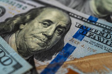 100 dolarlık banknotun yakın plan görüntüsü. Karmaşık detayları, güvenlik özelliklerini ve canlı renkleri vurguluyor. Finans, bankacılık ve zenginlik temaları için mükemmel