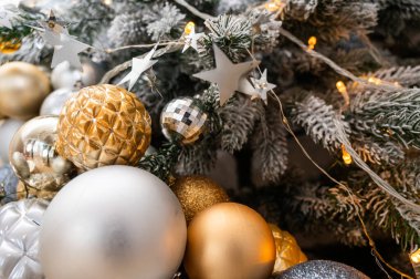 Süslü dalları, altın ve gümüş süslemeleri ve şenlikli ışıkları olan güzel dekore edilmiş bir Noel ağacının yakın çekimi. Tatil temaları, kış ve kutlama resimleri için mükemmel.