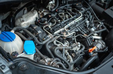 Close-up of a car engine with visible pipes, cables, and fluid reservoirs. Detailed view of automotive engineering, maintenance, and mechanical components for vehicle repair clipart