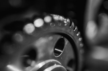 Metal dişliler ve mekanik parçaların siyah ve beyaz yakın plan görüntüleri endüstriyel ekipmanları, hassas mühendisliği ve mekanik süreçleri sembolize ediyor.