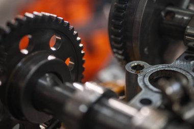 Hareket halindeki endüstriyel metal dişlilerin yakın görüntüsü, mühendisliği, makine yapımını, makine yapımı ve hassas imalatını, parçalanmış araba motorunu, yedek parçaları sembolize ediyor. Seçici odak