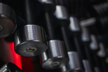 Spor salonundaki yeşil askıda siyah büyü dambıllarının yakın çekimi. Profesyonel antrenmanlar için dayanıklılık, spor, vücut geliştirme ve halter ekipmanları