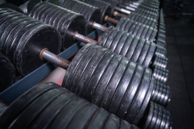 Spor salonundaki yeşil askıda siyah büyü dambıllarının yakın çekimi. Profesyonel antrenmanlar için dayanıklılık, spor, vücut geliştirme ve halter ekipmanları