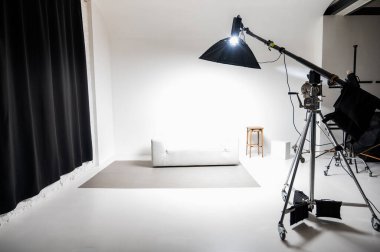 Softbox ışıklandırması, beyaz arka plan ve modern minimalist mobilyaları olan profesyonel fotoğraf stüdyosu. Ticari, portre ve ürün fotoğrafçılığı için ideal.