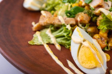 Lezzetli Sezar salatası ızgara tavuk, haşlanmış yumurta taze marul, mısır ve kremalı sos kahverengi bir tabakta. Mükemmel bir yemek için sağlıklı ve lezzetli bir yemek.