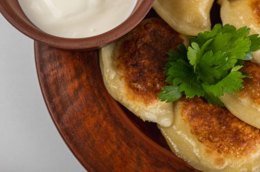 Ekşi kremalı çıtır altın hamur tatlısı (verenyky) ve kırsal bir tabakta taze maydanoz garnitürü. Geleneksel Doğu Avrupa mutfağı, doyurucu ve lezzetli.