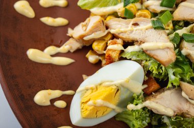 Lezzetli Sezar salatası ızgara tavuk, haşlanmış yumurta taze marul, mısır ve kremalı sos kahverengi bir tabakta. Mükemmel bir yemek için sağlıklı ve lezzetli bir yemek.