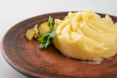 Eritilmiş tereyağlı kremalı patates püresi, turşu ve taze maydanozla süslenmiş. Ev yapımı yemekler ve konforlu yemek aşıkları için mükemmel bir meze.