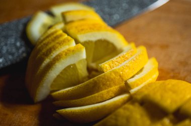 Keskin bir bıçakla tahta kesme tahtasının üzerinde taze kesilmiş limon. Parlak turunçgil meyvesi, C vitamini bakımından zengin, yemek, içki ve sağlıklı yaşam tarzı için ideal, virüs önleme, seçici odaklanma