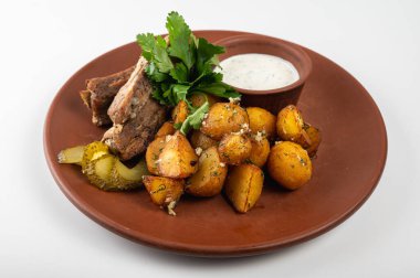 Lezzetli ızgara domuz pirzolası, kızarmış patates, turşu ve kırsal bir tabakta taze maydanoz. Kremalı beyaz sosla servis edilir. Mükemmel ev yemeği.